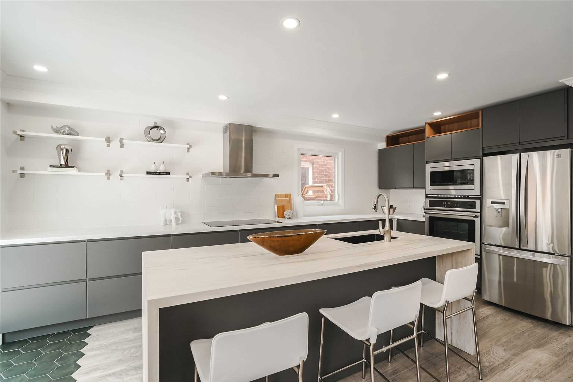 Completed modern kitchen with an oversized island, two-tone cabinetry and integrated appliances